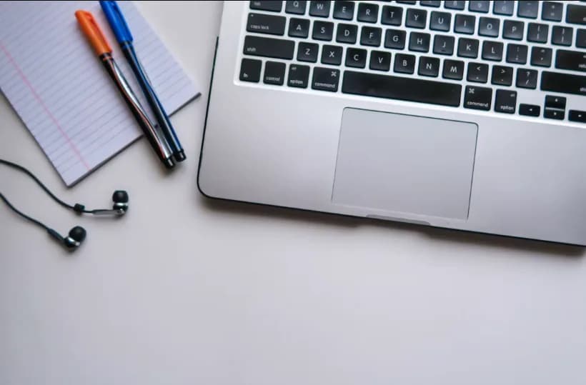 Laptop, notebook, pens, and earphones on a desk for planning an online degree and career change