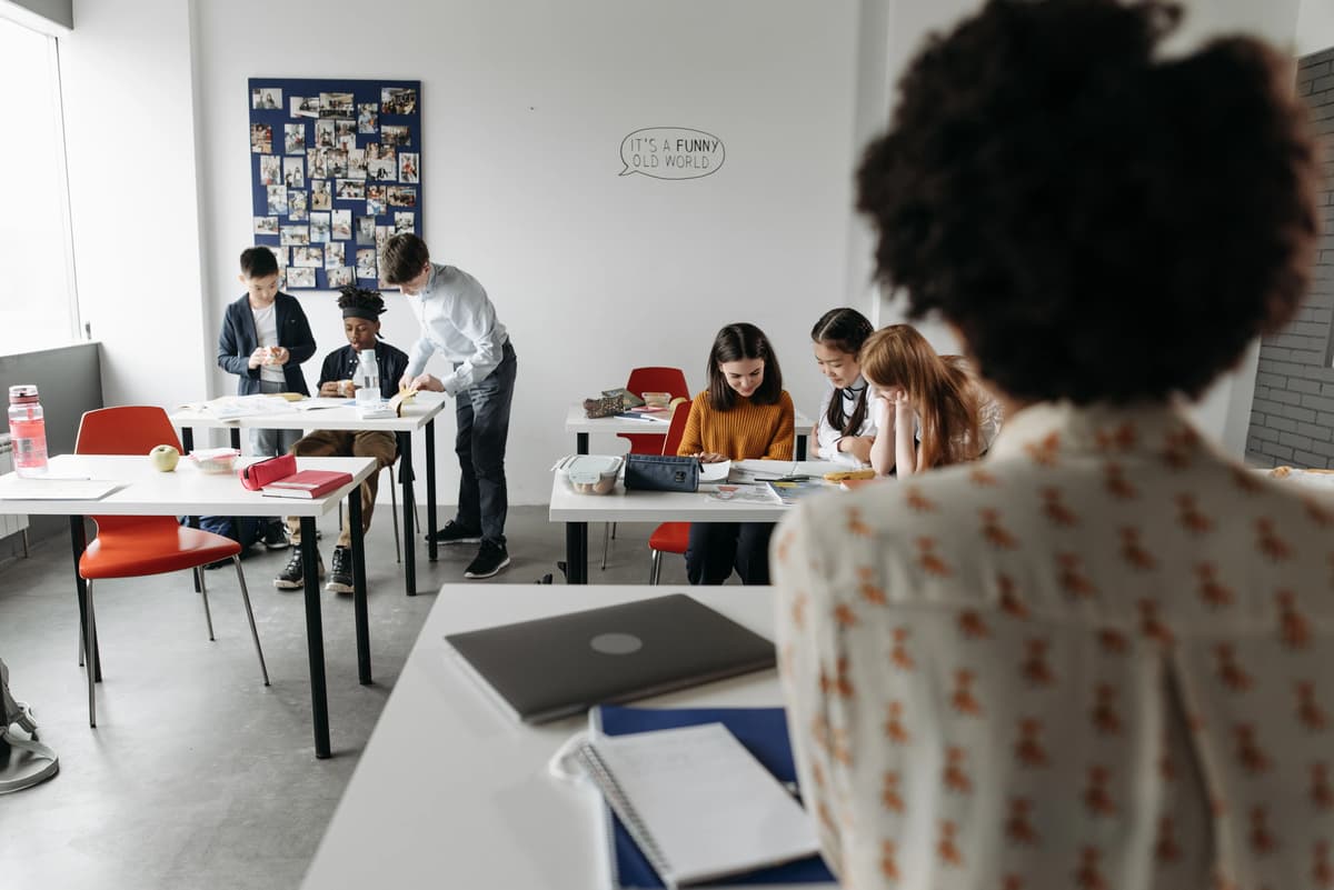 Teacher addressing students collaborating in small groups in a classroom