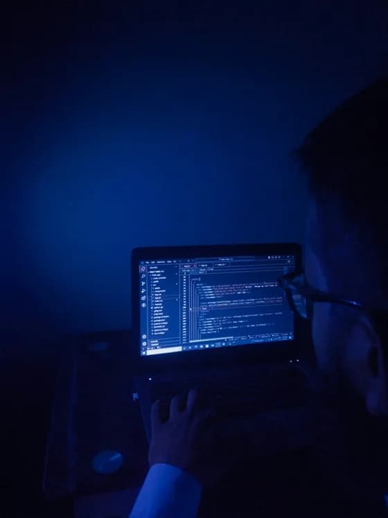 "Real human AI developer engineering in 2026 coding artificial intelligence software on a laptop in a dark tech workspace, showcasing Refonte Learning’s hands-on training in Python and machine learning environments."