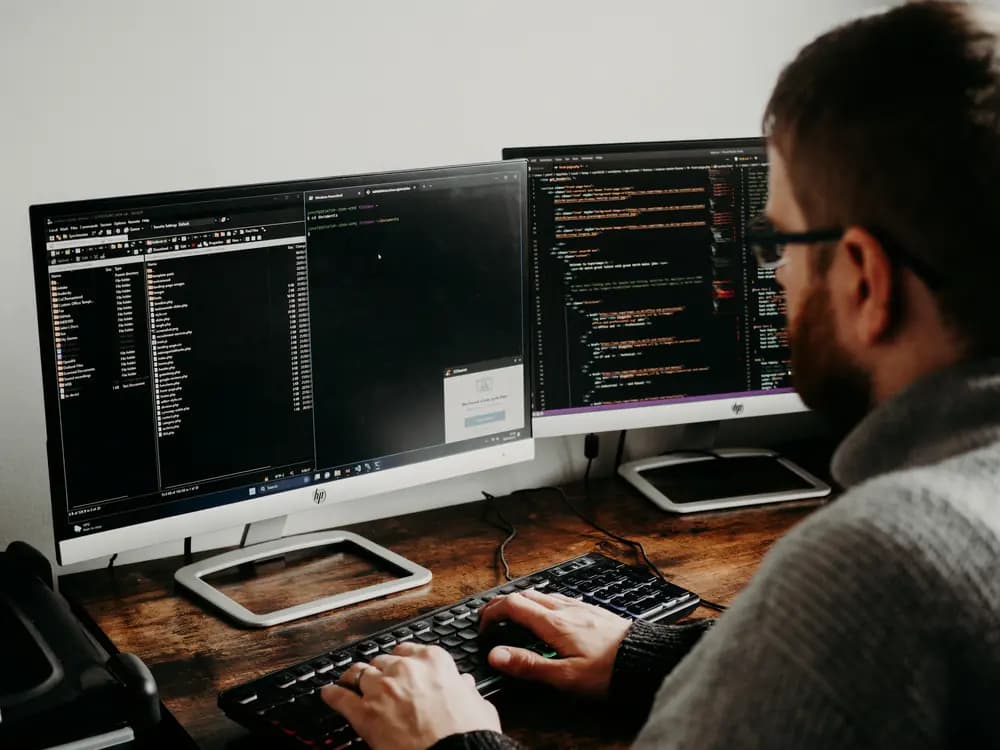 Backend engineer working on AI-powered backend architecture, using multiple monitors to build scalable, intelligent systems and data-driven services.