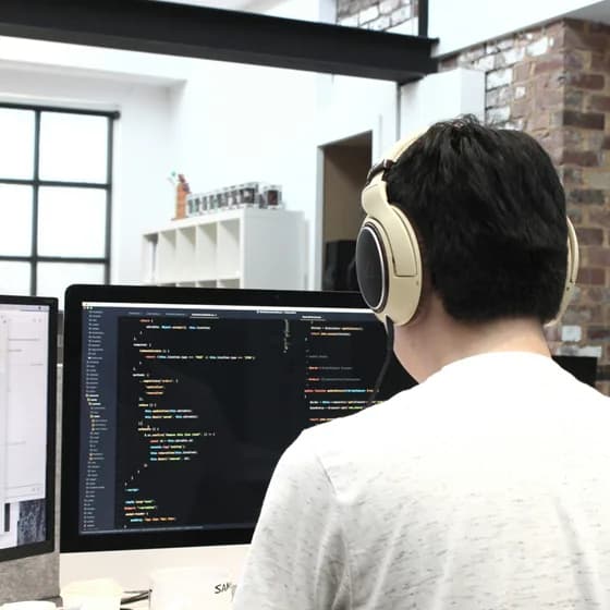 A back-end development engineer coding with focus and headphones, building the invisible backbone of modern applications.