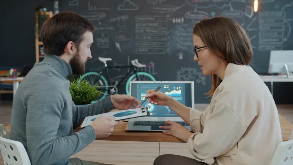 Two colleagues reviewing data on a laptop, symbolizing collaborative data-driven innovation