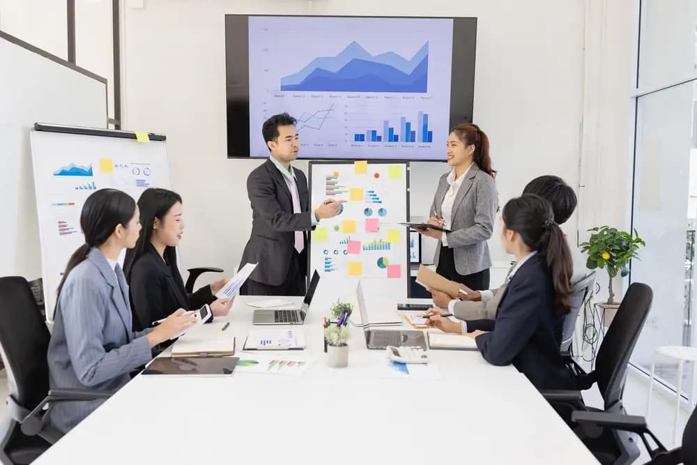 Business analytics team collaborating in a modern office, analyzing dashboards and data insights during a strategy meeting, illustrating business-analytics-program in 2026 with Refonte Learning