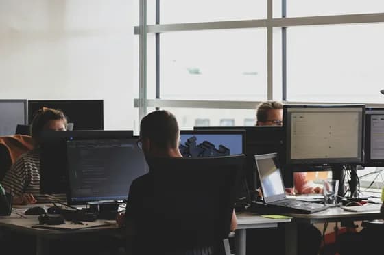 Cloud security engineers collaborating in a modern office environment, analyzing code and cloud infrastructure dashboards as part of cloud security engineering best practices in 2026 by Refonte Learning
