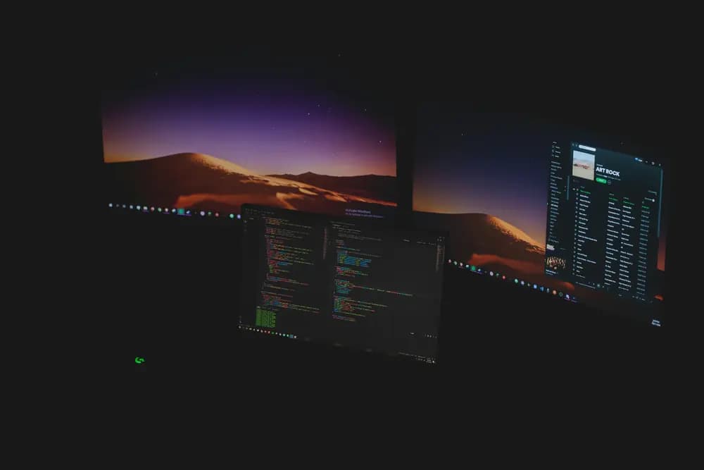 Cloud security monitoring workspace with multiple screens displaying source code, system logs, and cloud infrastructure dashboards used to secure modern cloud environments.
