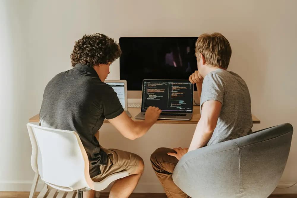 Cybersecurity engineers collaborating on code review and security analysis, working on laptops to protect software systems and digital infrastructure.