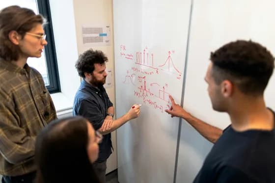 A team of data engineers and analysts collaborating on a data pipeline design in a modern workspace. Real-world data engineering is a team effort, requiring close collaboration between engineers, analysts, and other stakeholders to turn raw data into actionable insights