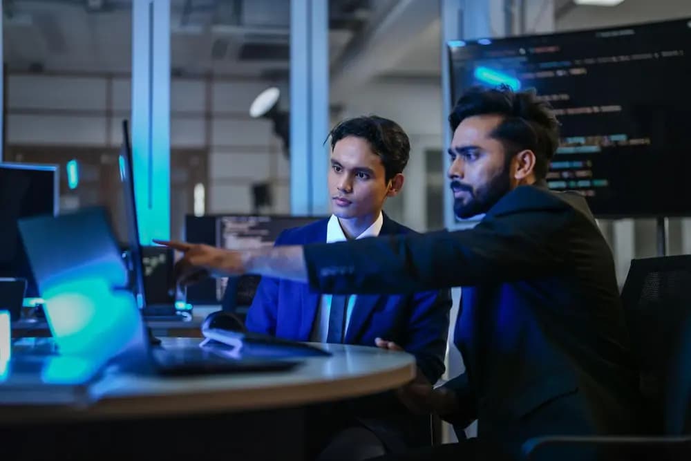 Real AI developers collaborating on model review, prompt testing, and cloud deployment in a modern engineering workspace.
