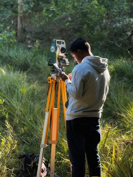 A geospatial professional in the field using precision instruments. Modern remote sensing experts blend field data collection, like surveying, with advanced satellite and drone imagery analysis to build comprehensive geospatial insights.