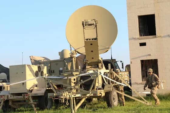 Satellite communications engineers often work with both cutting-edge space technology and ground infrastructure. In this real-world scene, engineers set up a satellite transmission terminal with a large deployable antenna, ensuring robust communication links during an operation. Teamwork and technical expertise are key in handling the sophisticated equipment that connects earth stations to orbiting satellites