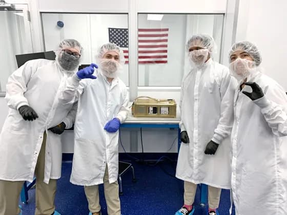 Satellite engineers working in a cleanroom to assemble and test a small satellite. Real-world, hands-on work is a core part of satellite engineering, often involving teams of specialists collaborating on spacecraft components.