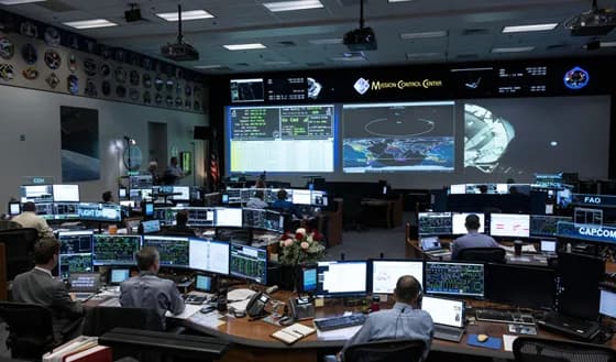 Flight controllers in NASA’s mission control center monitor a critical engine burn during the Artemis I mission (2022). Satellite operations specialists work in similar environments to oversee and control space missions.