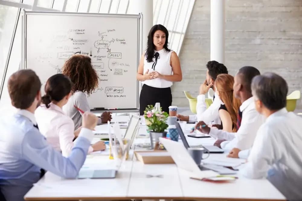 Scrum master in 2026 leading agile sprint planning meeting with diverse cross-functional team in modern office discussing AI-driven project strategy and DevOps workflow on whiteboard
