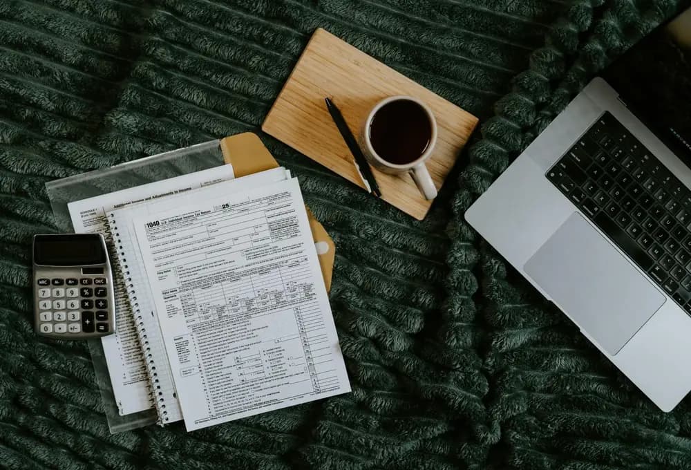 aptop, calculator, coffee, and printed spreadsheets for student business planning