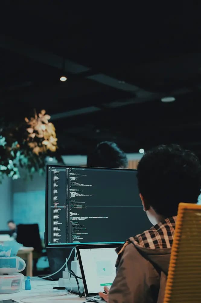 DevOps engineer working on multiple screens, managing code, automation, and cloud infrastructure as part of modern DevOps engineering workflows.