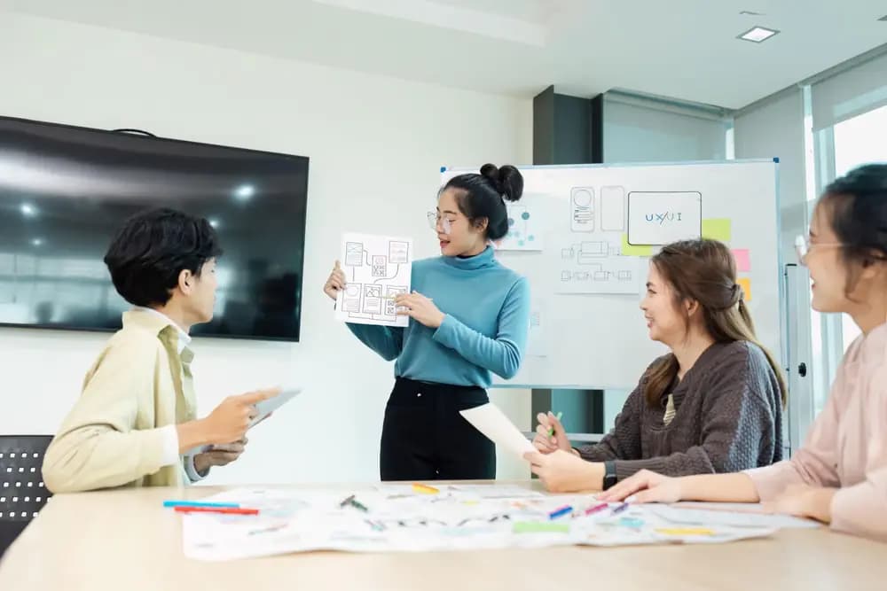 UI/UX designers collaborating on wireframes, user flows, and prototype decisions during a real product workshop in 2026.