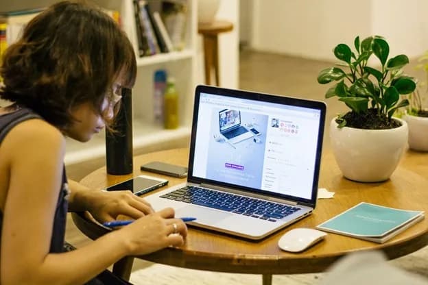 Student studying an online STEM course on a laptop at home with notes, a notebook, and a study desk setup.
